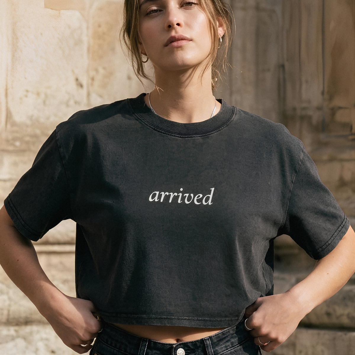 A close-up of a person wearing a dark charcoal crewneck t-shirt with a white skull graphic and the text 'ever & after' on the chest, set against a dark stone wall background.