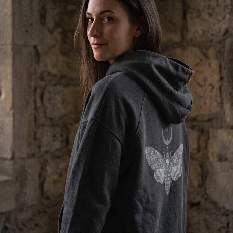 Gray hoodie with Medusa graphic on a concrete surface with candles and an open book.