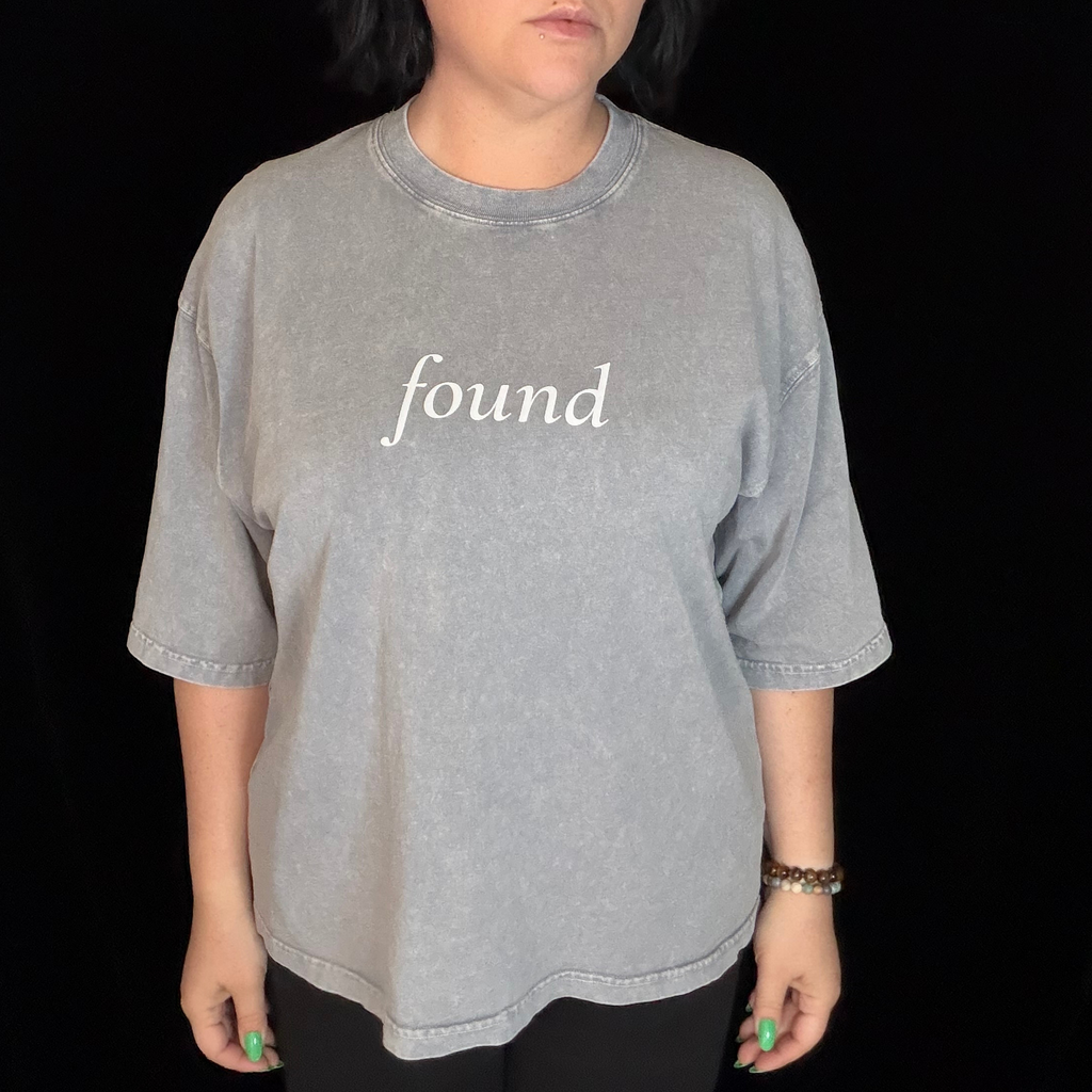 alt millennial woman wearing light gray boxy tee with text found on the center chest