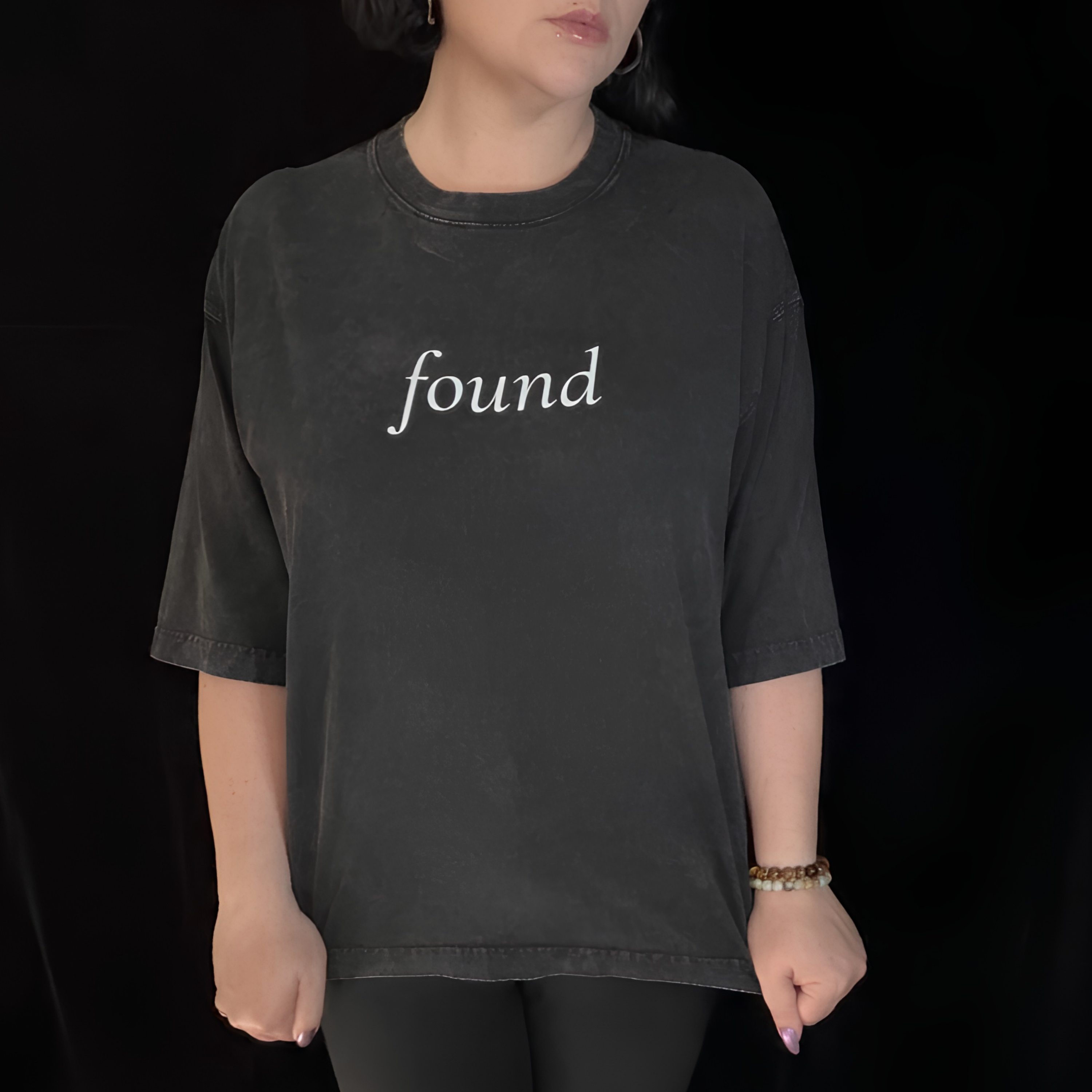 alt millennial woman wearing faded black boxy tee with text found on the center chest