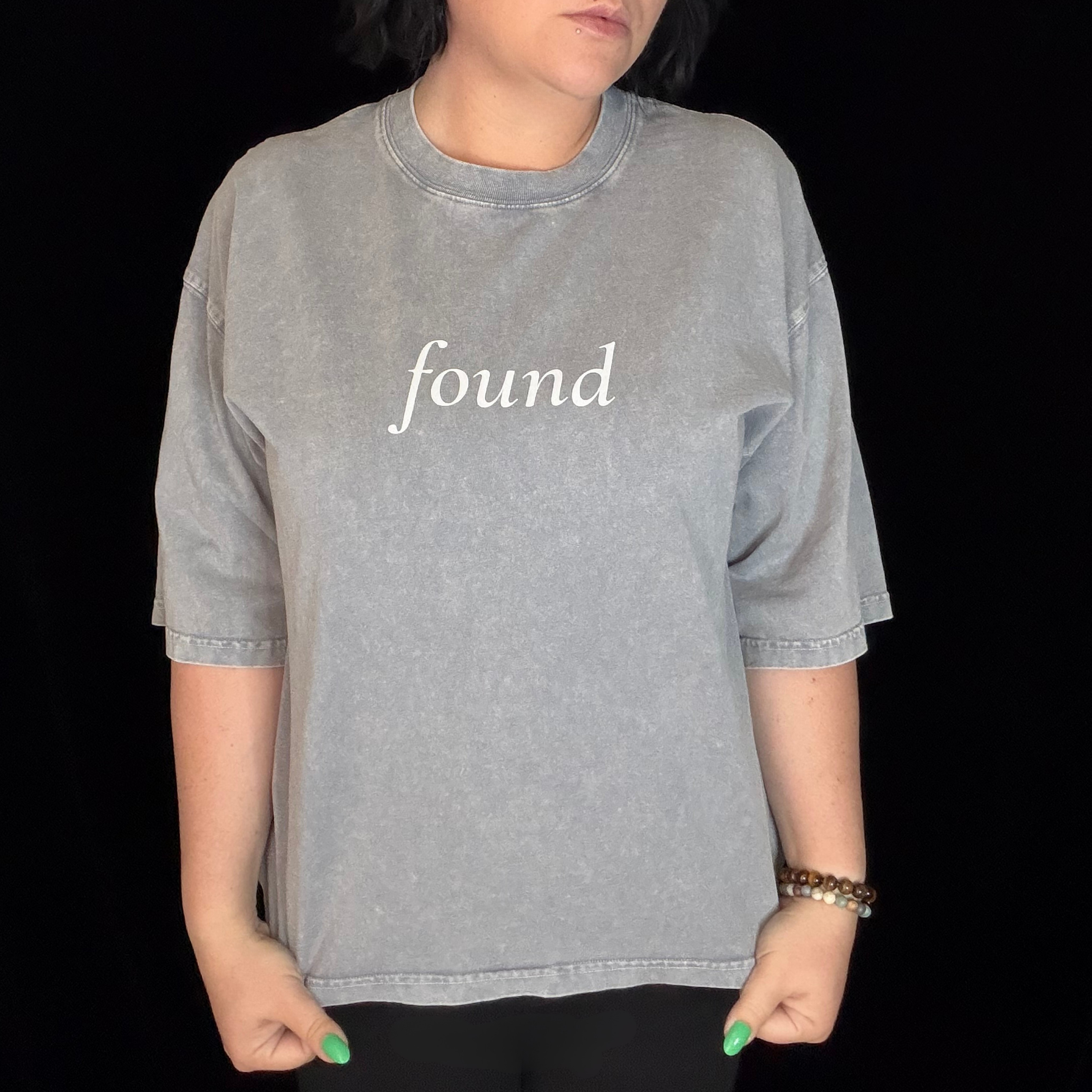 alt millennial woman wearing light gray boxy tee with text found on the center chest