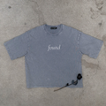 light gray boxy tee layflat on concrete with rose text found on center chest