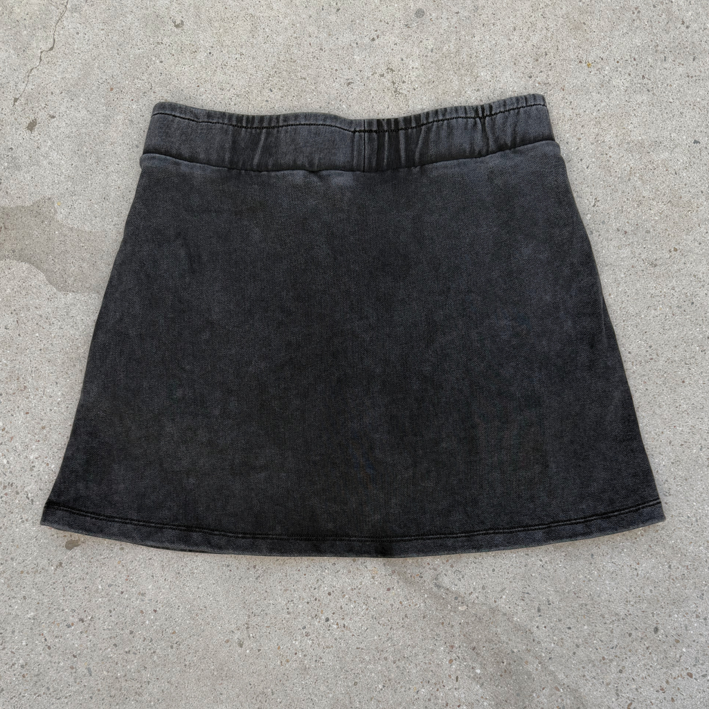 Black denim skirt on a concrete surface