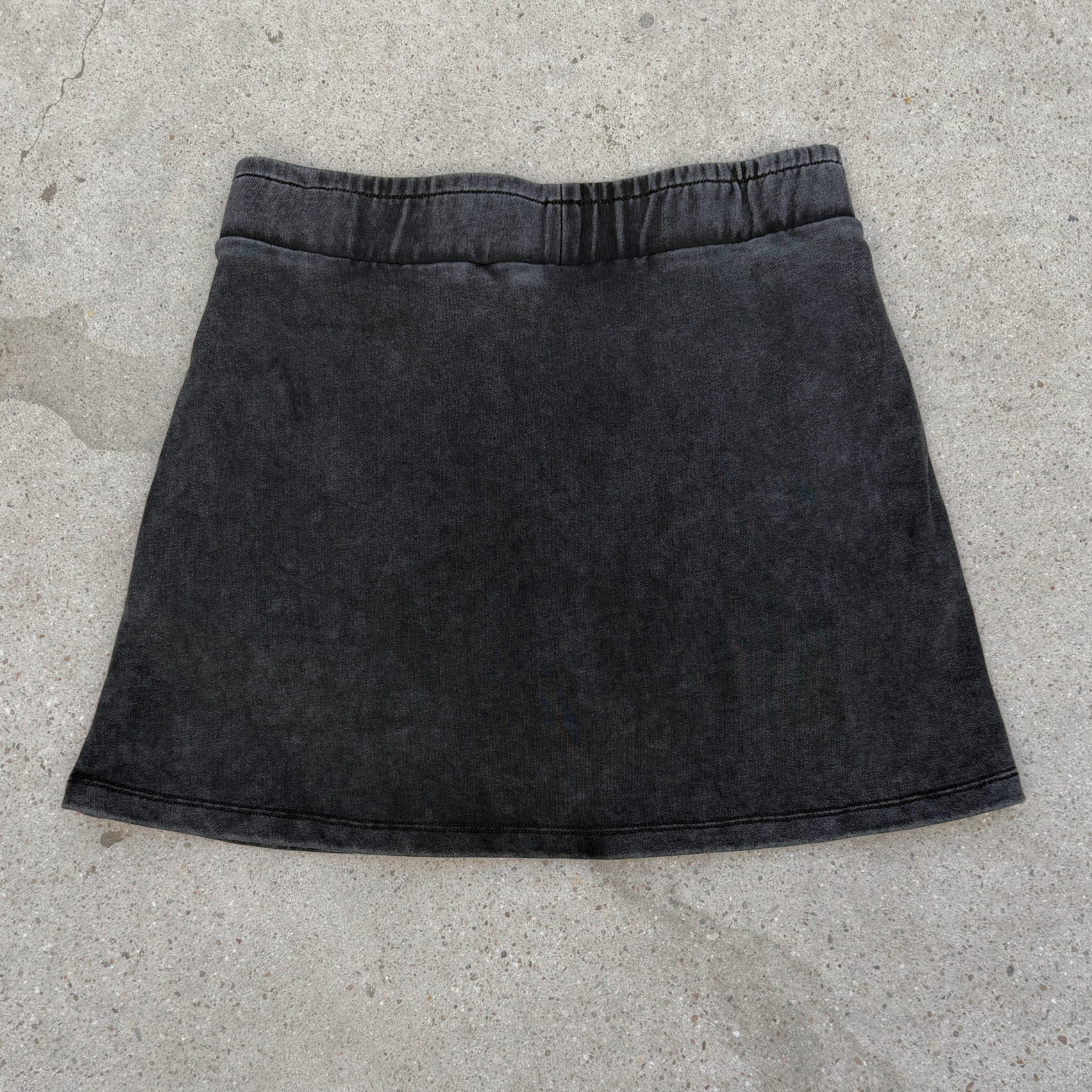 Black denim skirt on a concrete surface