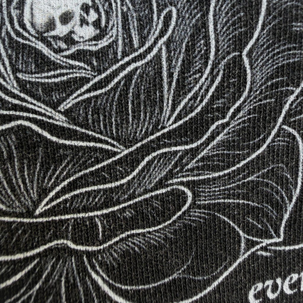 Black and white illustration of a skull within a rose on a textured black background.