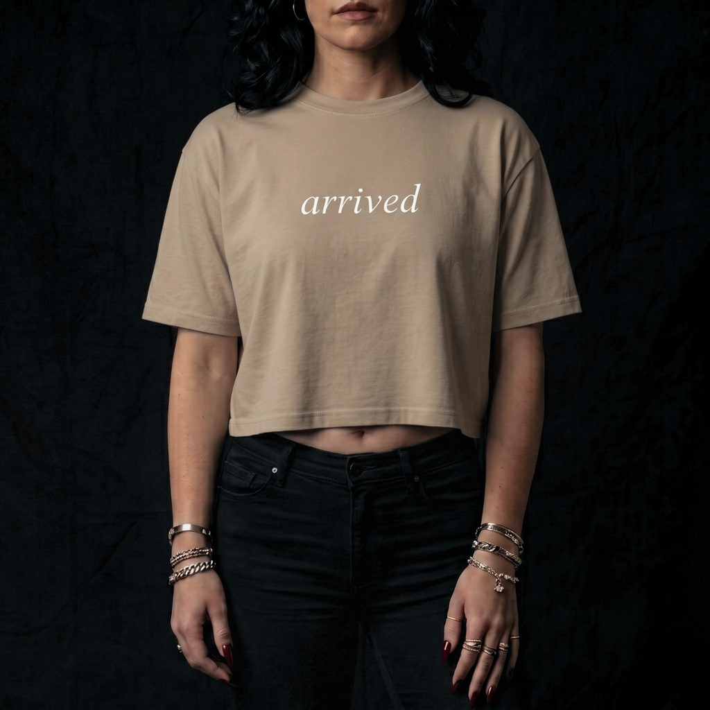 Person wearing a beige t-shirt with 'arrived' text on a black background