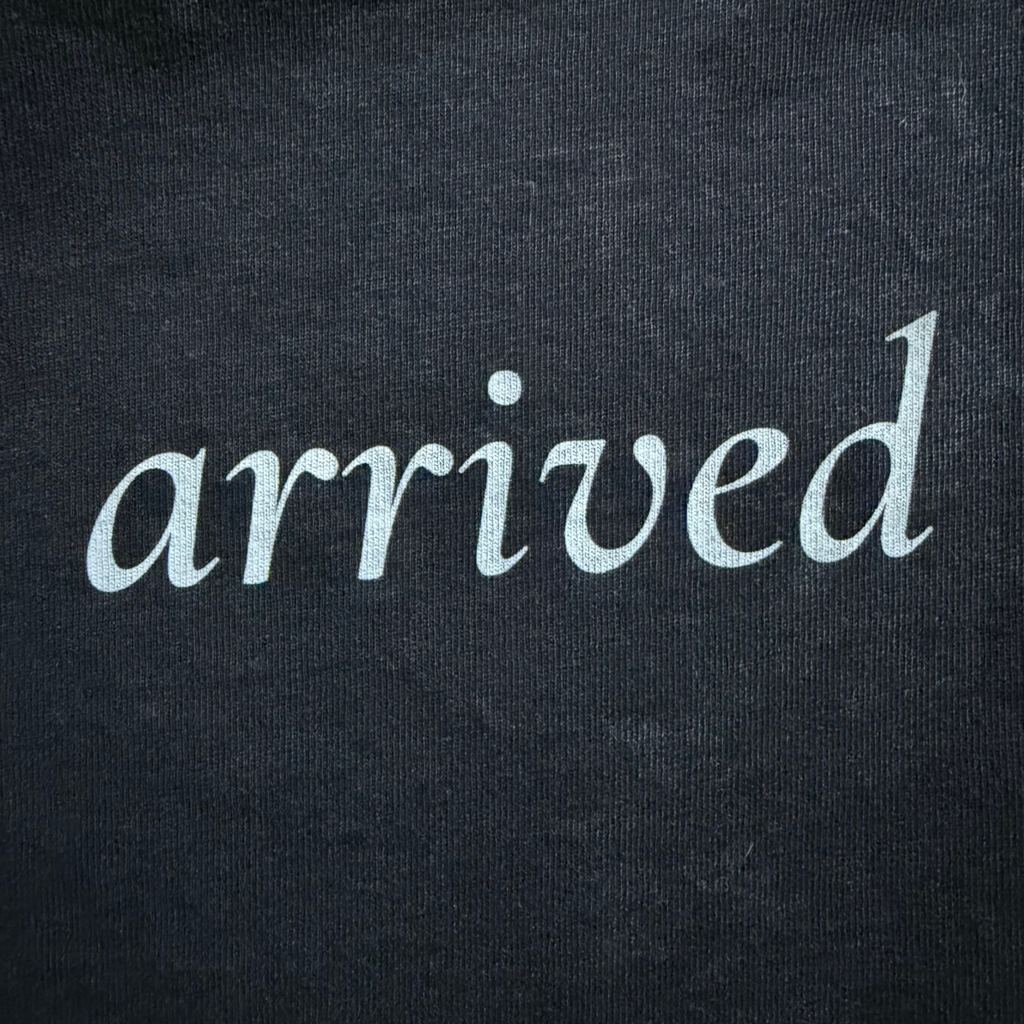 Text 'arrived' on a black tee