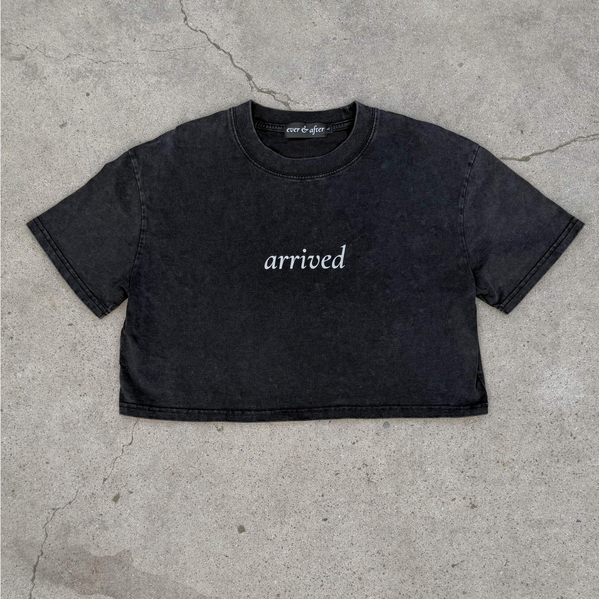 Black t-shirt with 'arrived' text on a concrete surface