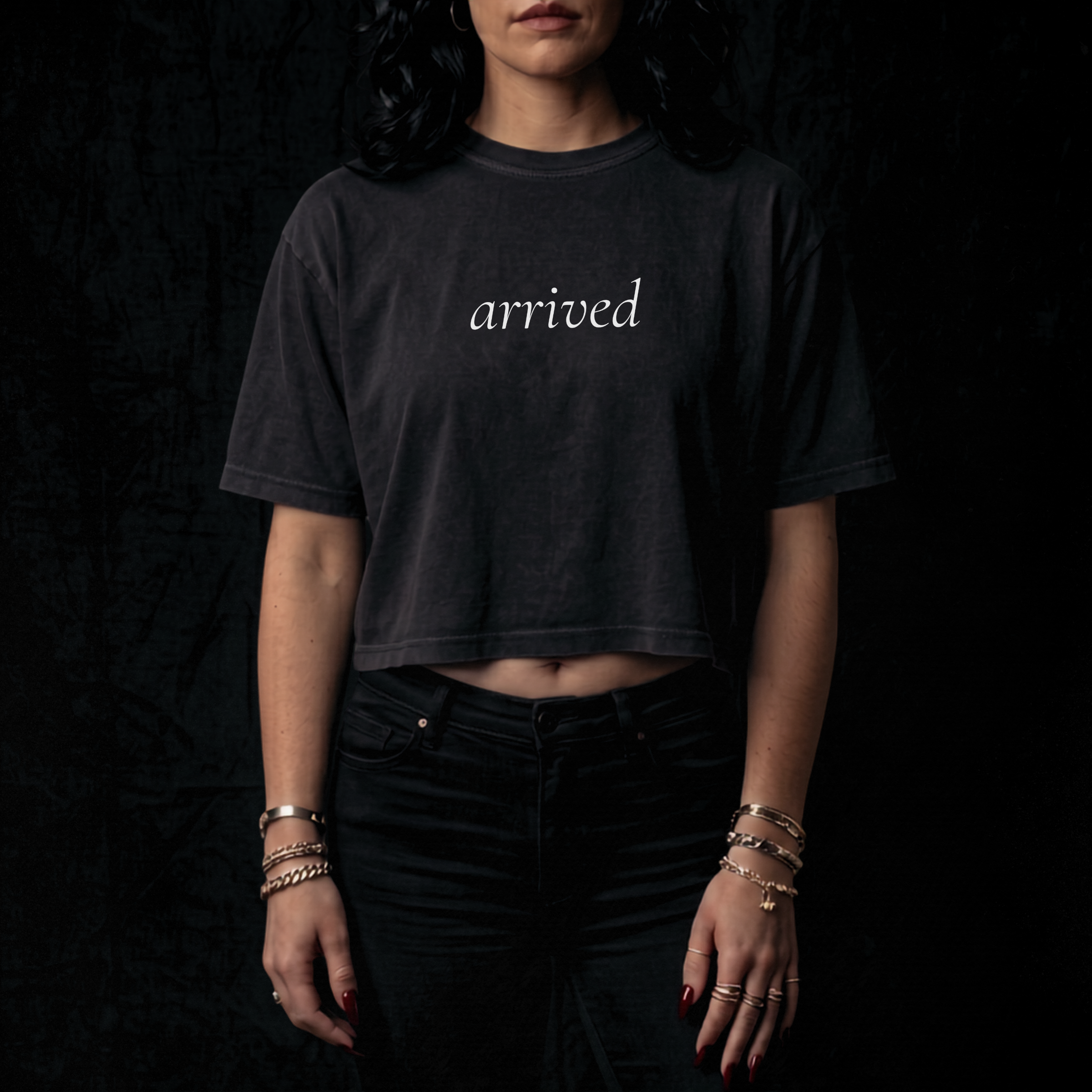Person wearing a black t-shirt with 'arrived' text on a dark background