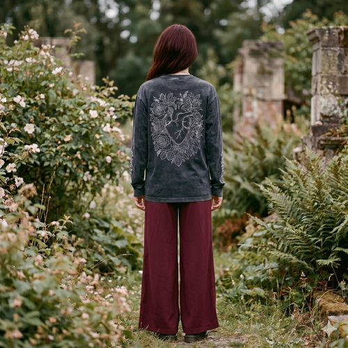 Person wearing a dark long-sleeve shirt with floral designs in a garden setting