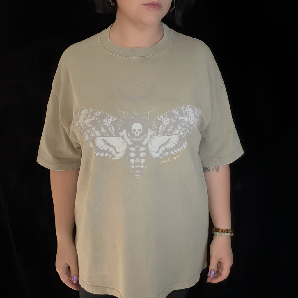 alt millennial woman wearing snow wash bone wash oversized tee with moth and moon design center on chest and brand word mark underneath