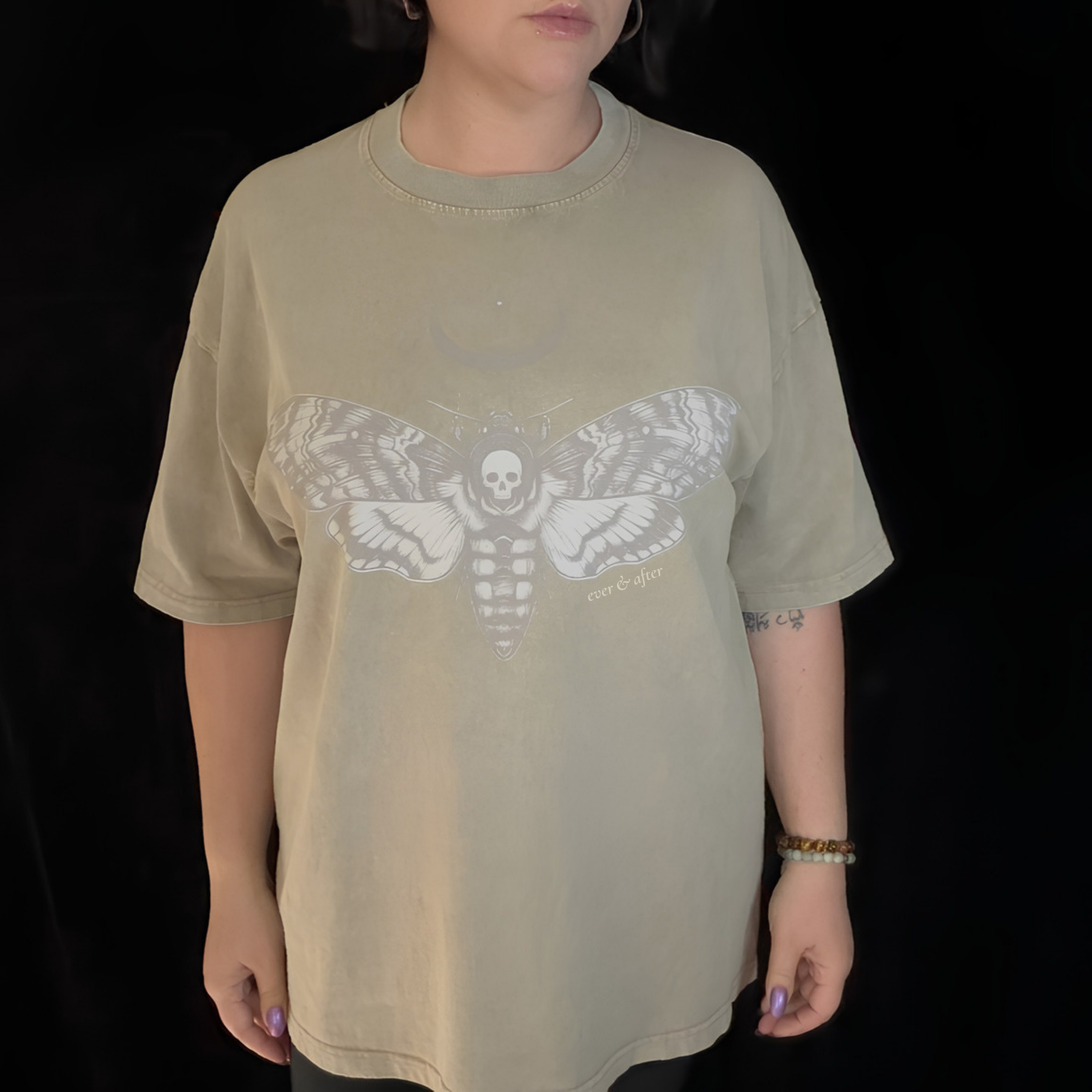 alt millennial woman wearing snow wash bone wash oversized tee with moth and moon design center on chest and brand word mark underneath