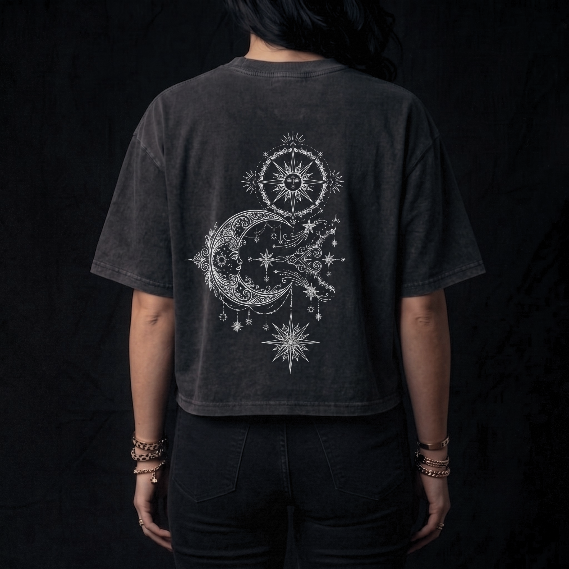 Person wearing a black t-shirt with celestial design on the back against a dark background