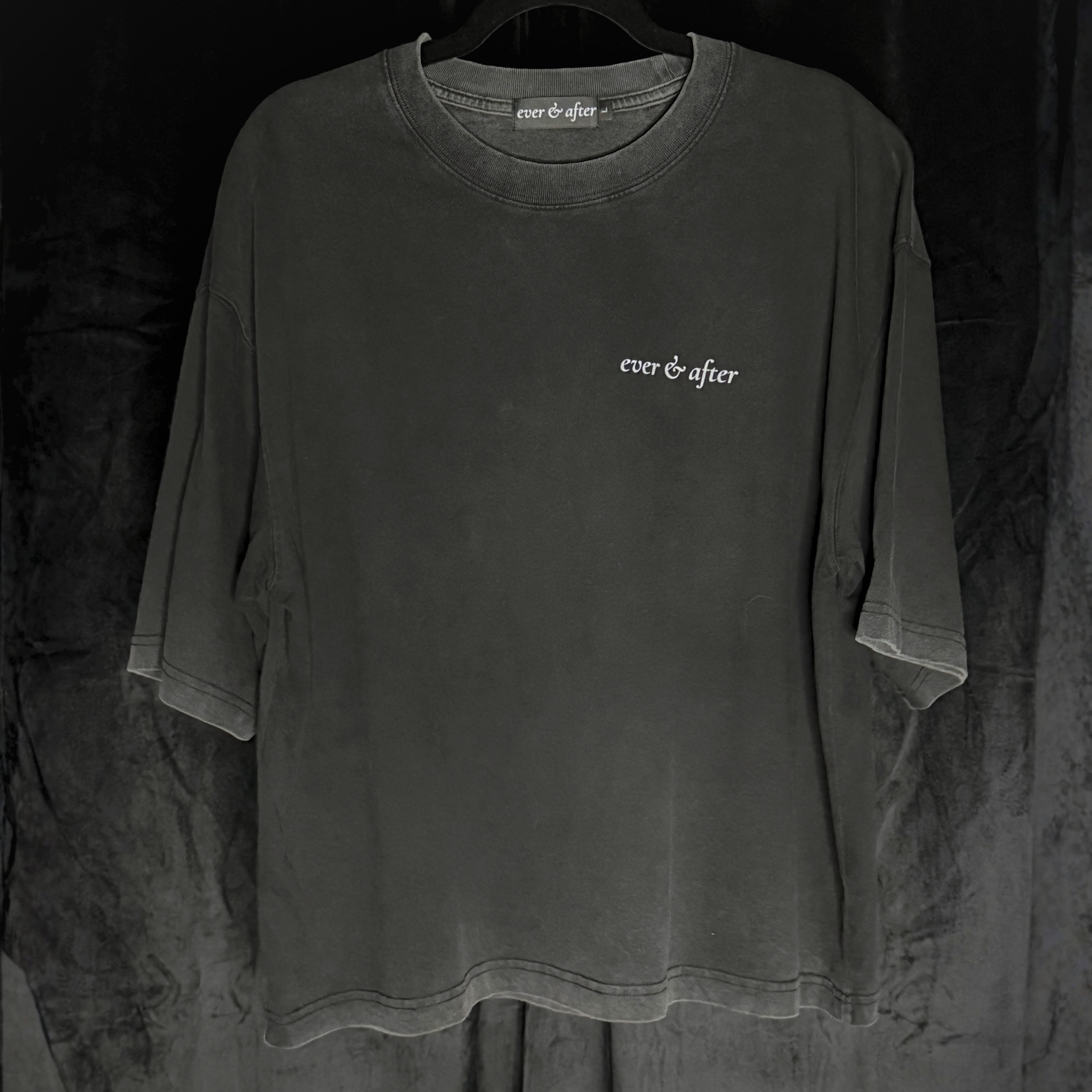 Dark gray t-shirt with 'ever & after' logo on a hanger against a dark background