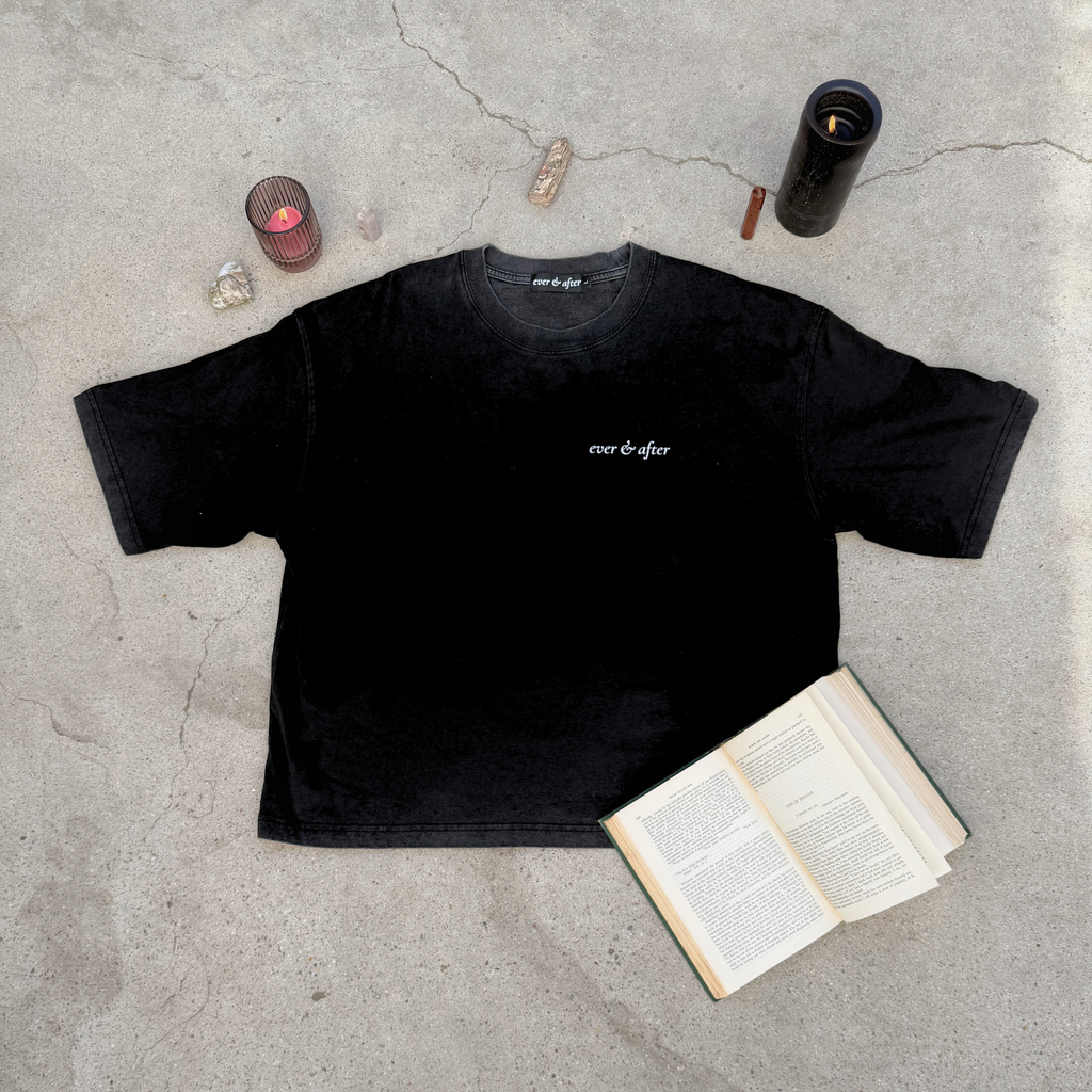 Black t-shirt with 'ever after' text on a concrete surface with candles and an open book.