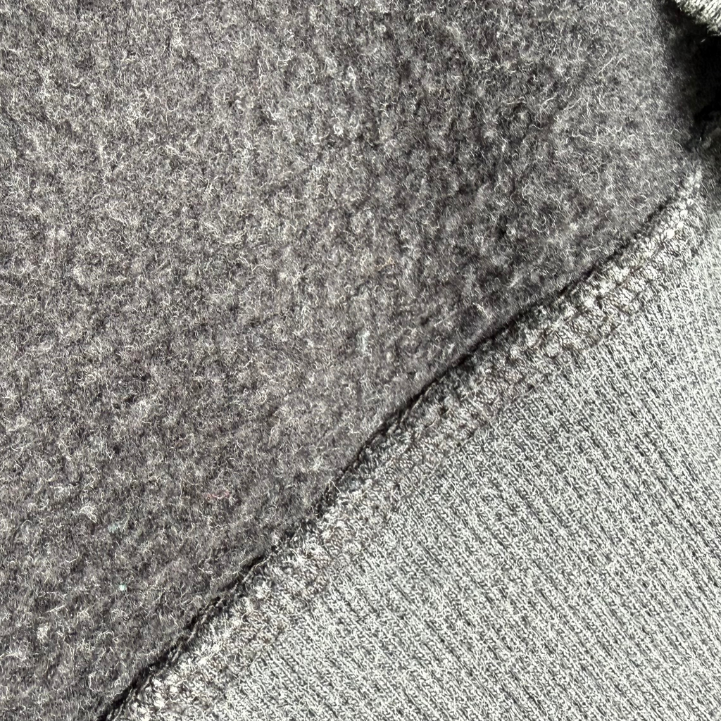 Close-up of a gray knit fabric with a ribbed edge and a textured, fuzzy gray backing or lining.