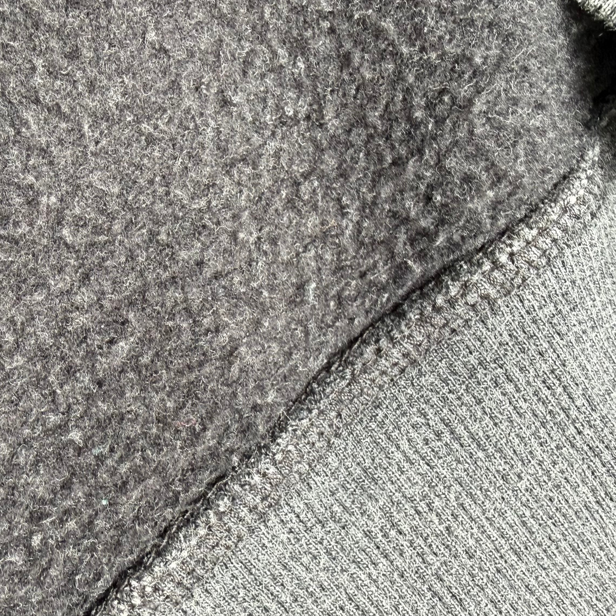Close-up of a gray knit fabric with a ribbed edge and a textured, fuzzy gray backing or lining.