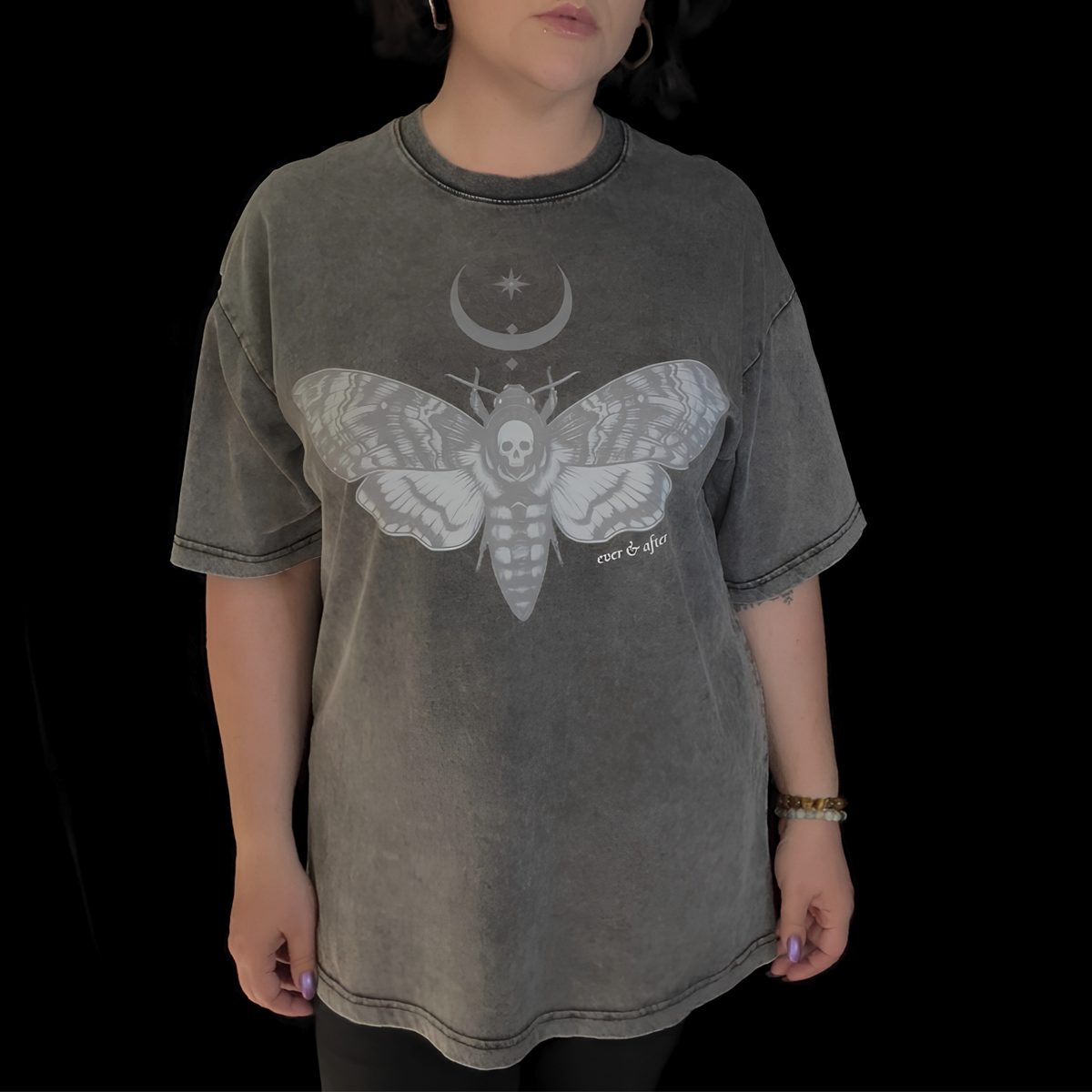Person wearing a dark gray t-shirt with a graphic design on a black background