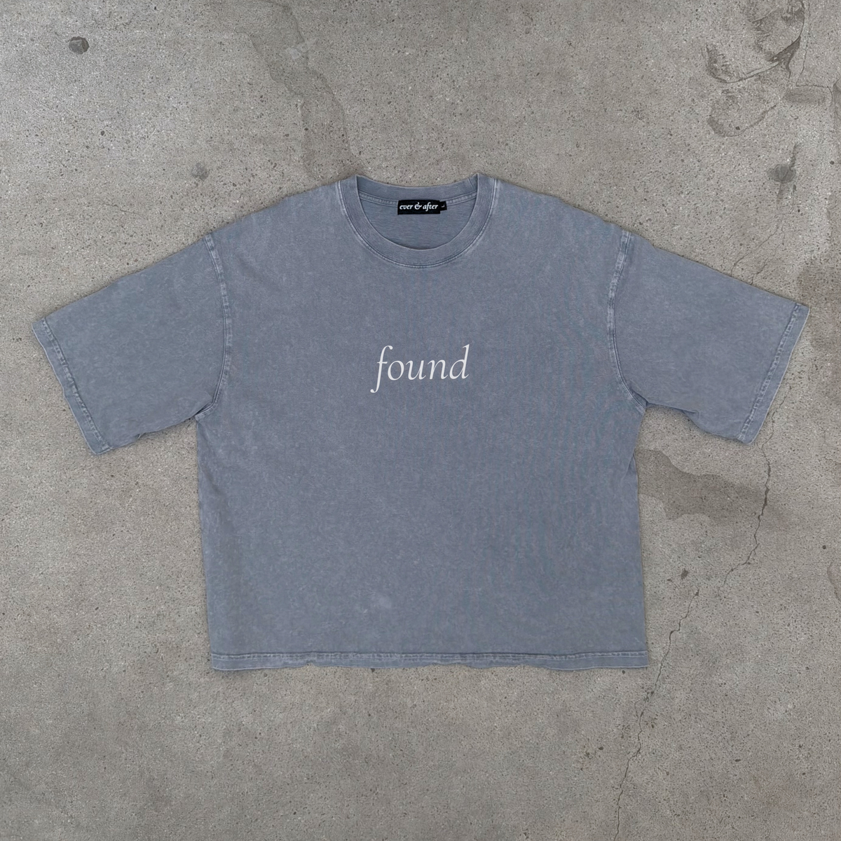 Blue-gray t-shirt with 'found' text on a concrete surface