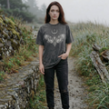 Woman standing on a path in a natural setting wearing a dark t-shirt with a graphic design.