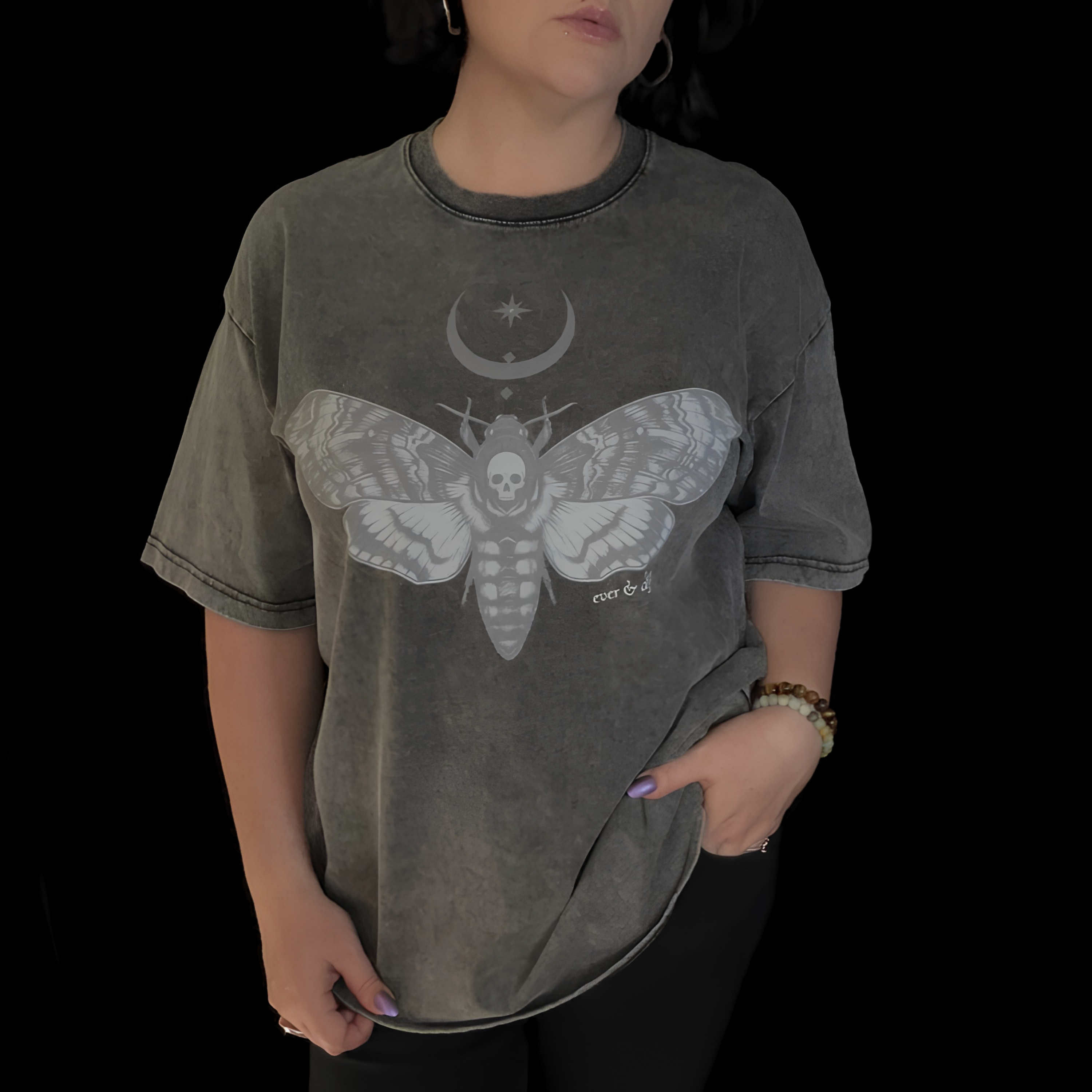 alt millennial woman wearing snow wash dark gray oversized tee with moth and moon design center on chest and brand word mark underneath