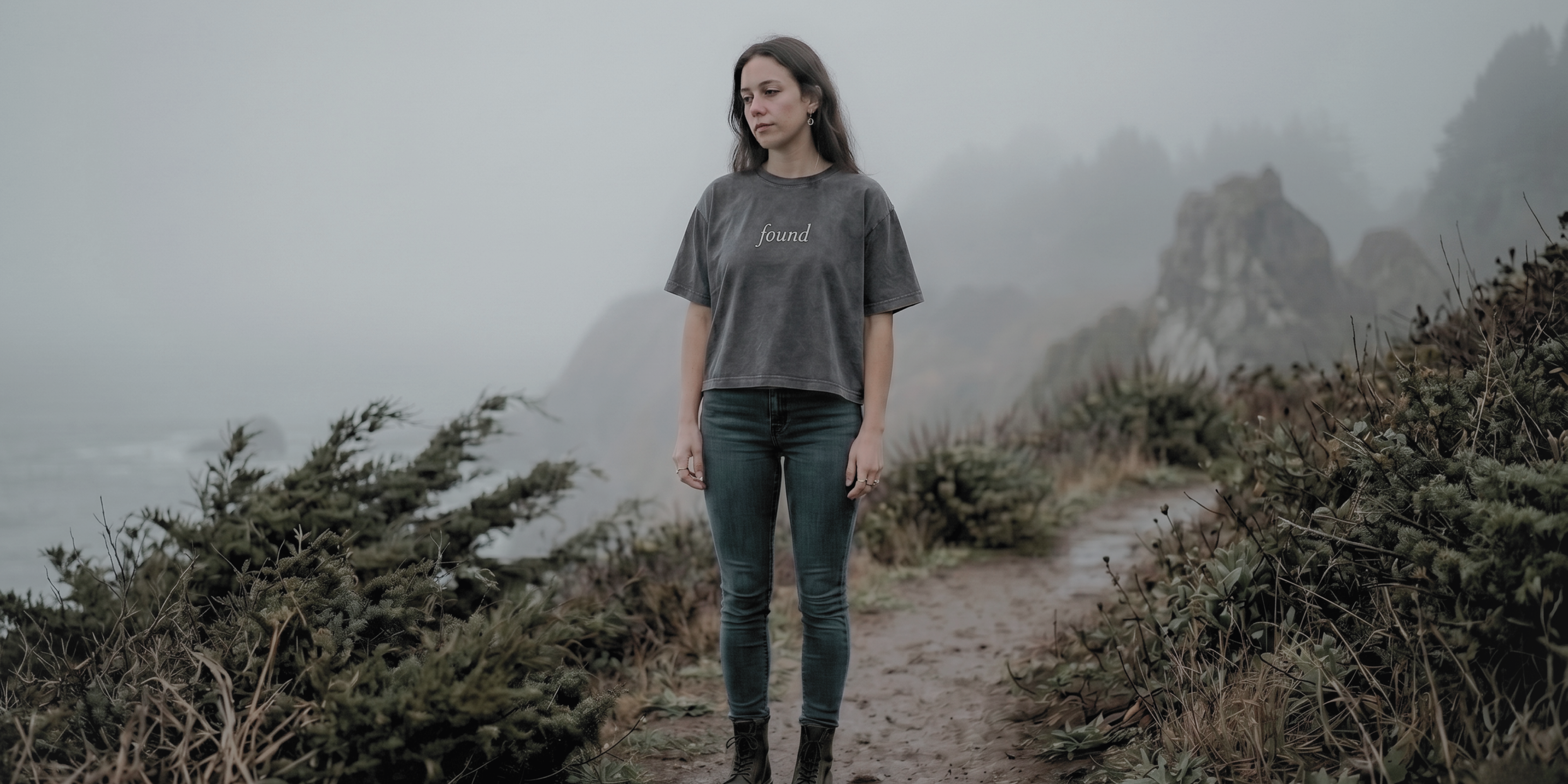 homepage hero image of millennial alt woman wearing faded noir found boxy tee on foggy path