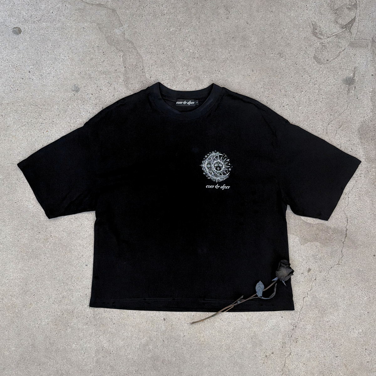 Black t-shirt with a white logo on a gray concrete surface