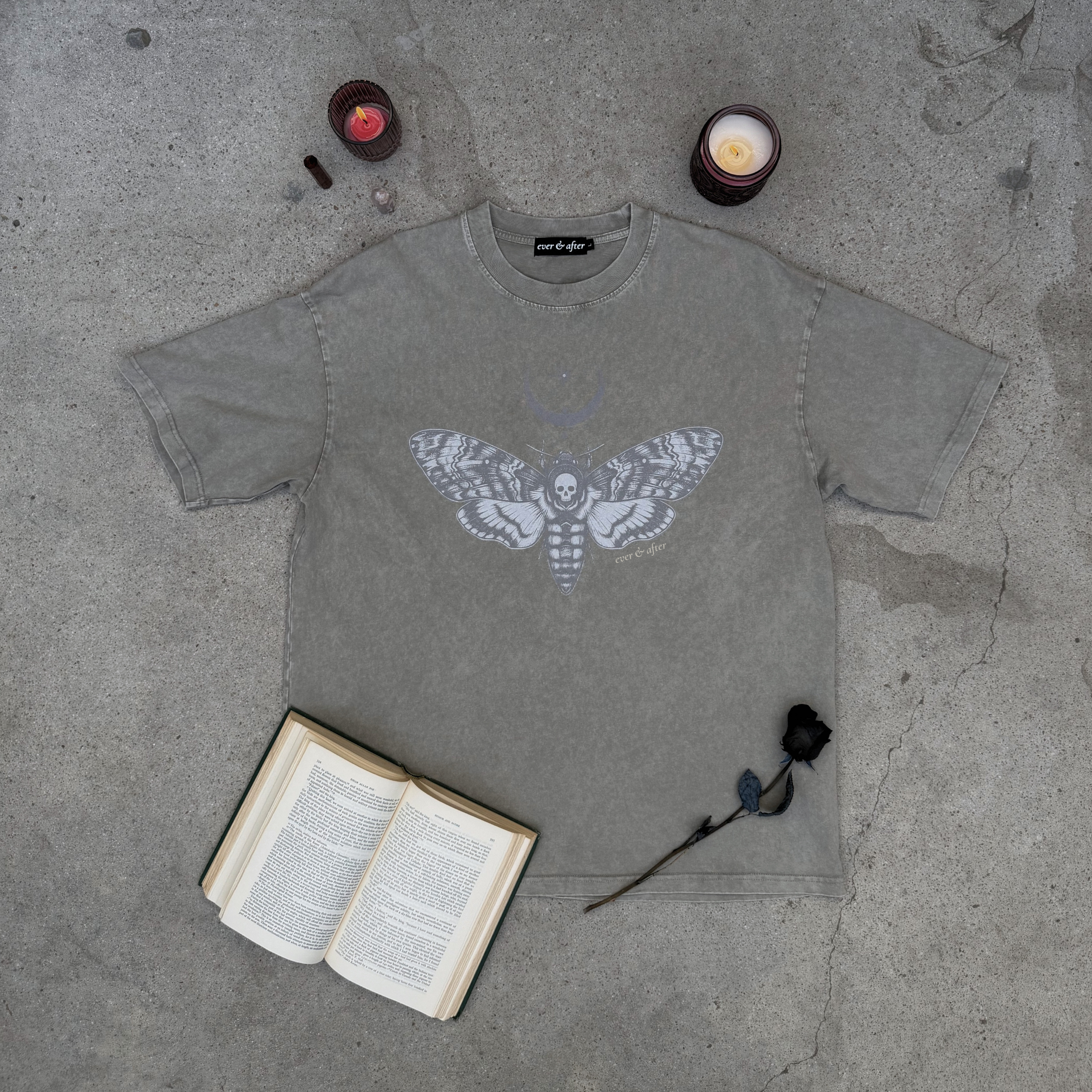 bone wash oversized moth tee lay flat on concrete with rose, candles, old book, and cystals