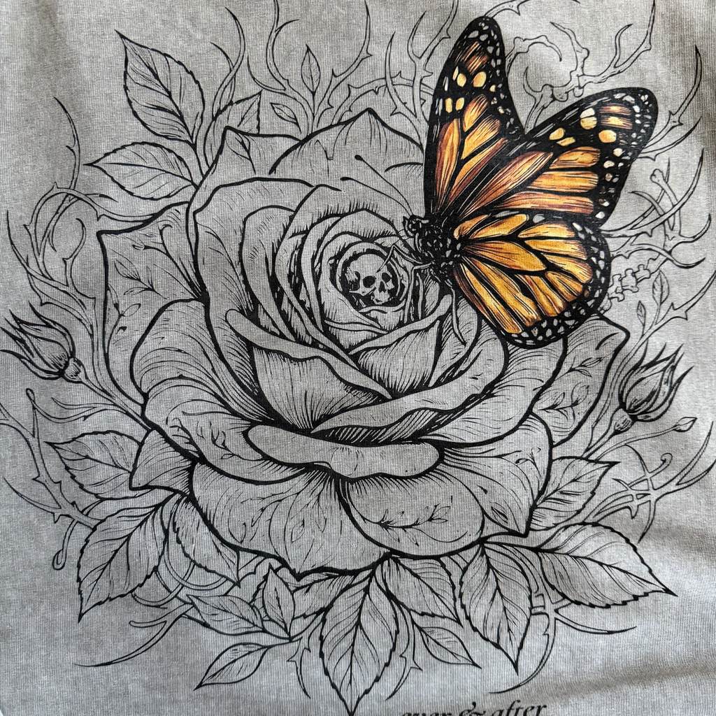 close up detail of rose and butterfly design on light gray tee