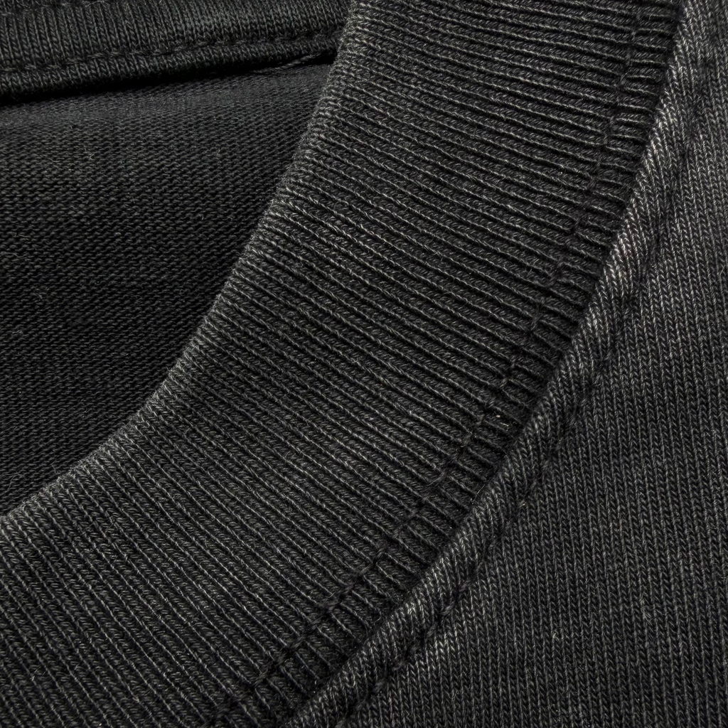 Close-up of a dark charcoal gray ribbed knit fabric, showing the texture and stitching detail of a garment.