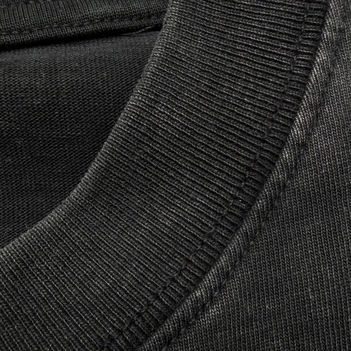 Close-up of a dark charcoal gray ribbed knit fabric, showing the texture and stitching detail of a garment.