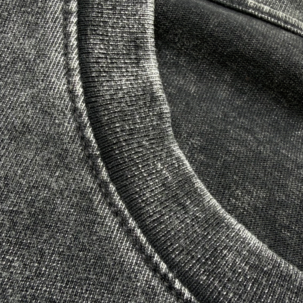 Close-up of a dark gray heathered cotton t-shirt fabric, showing the ribbed crew neck collar and textured weave.