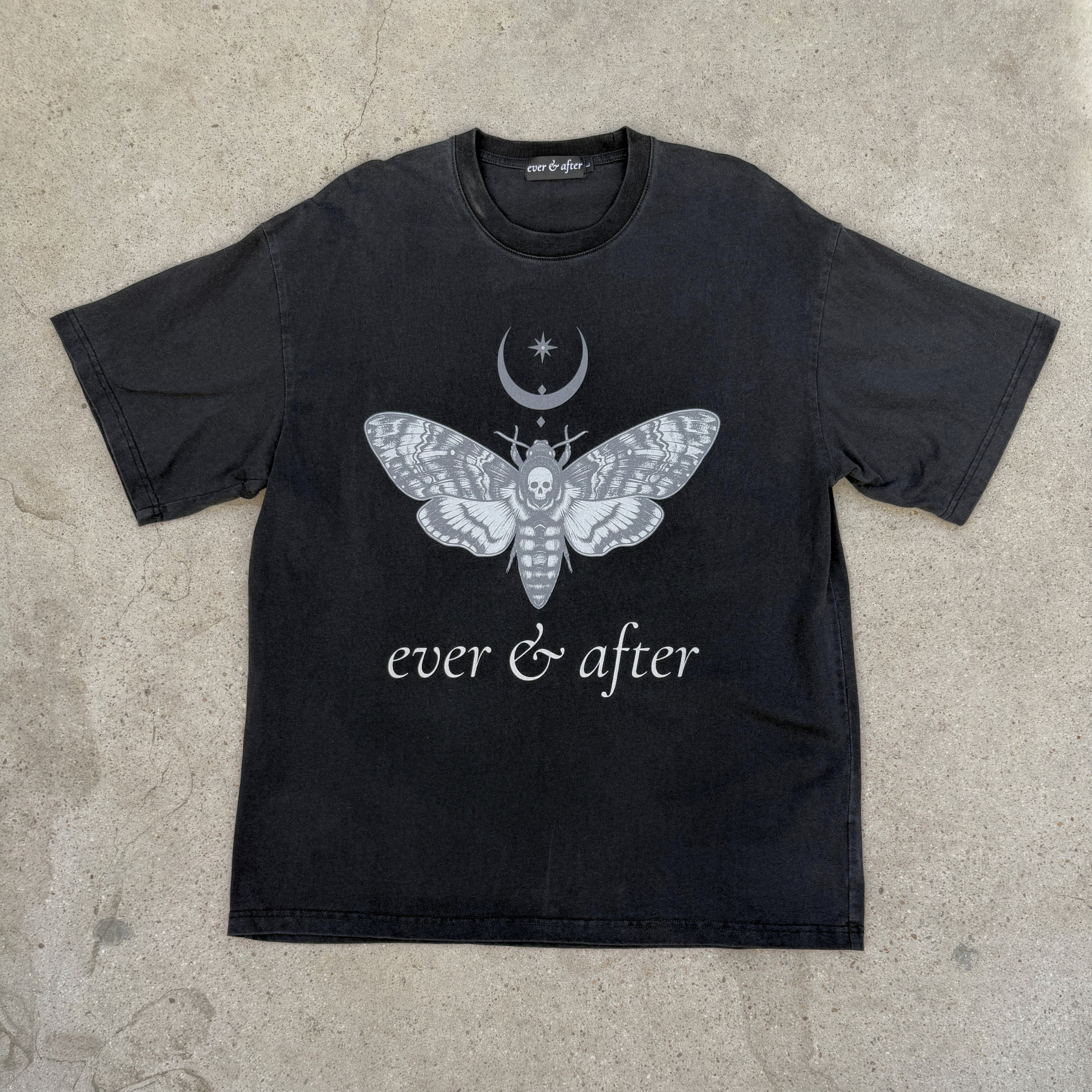Black t-shirt with a white moth design and 'ever & after' text on a concrete surface