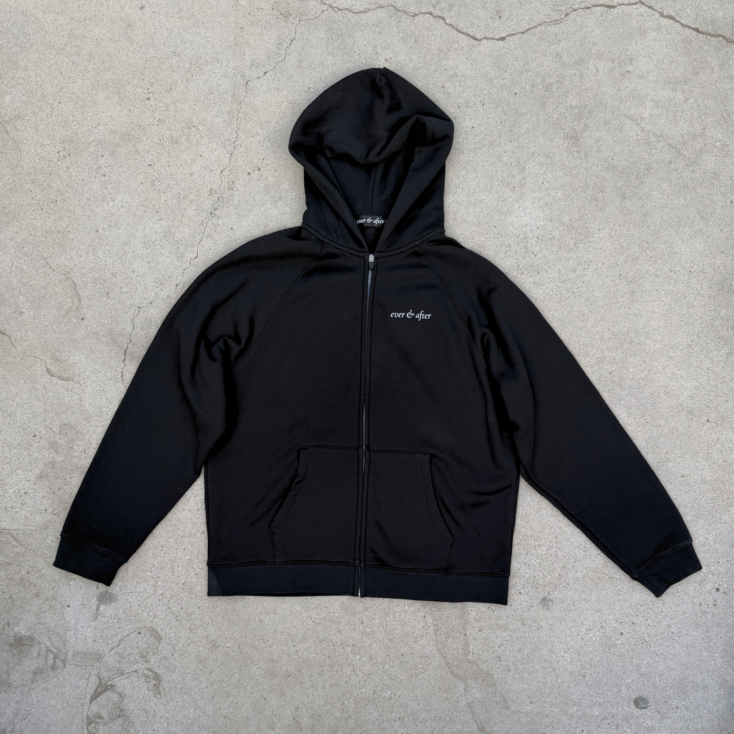 Black hoodie with a brand logo on a concrete floor