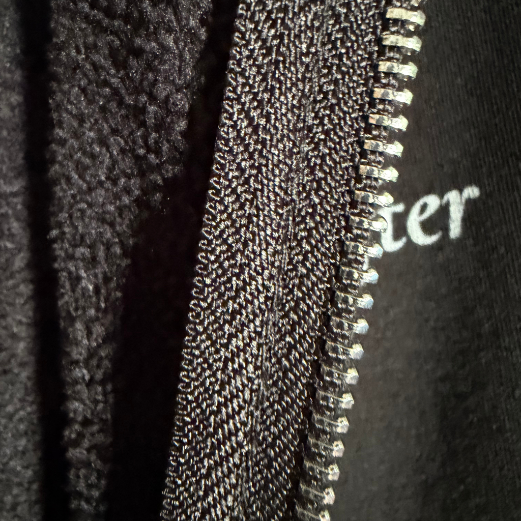 Close-up of a zipper on a textured fabric background with 'Winter' text.
