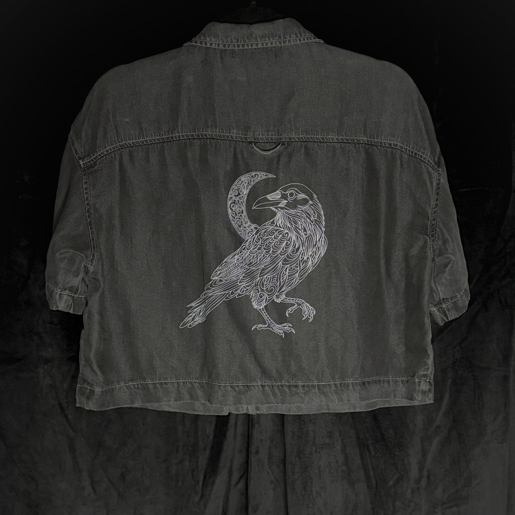 Dark denim jacket with a bird and moon design on the back against a black background
