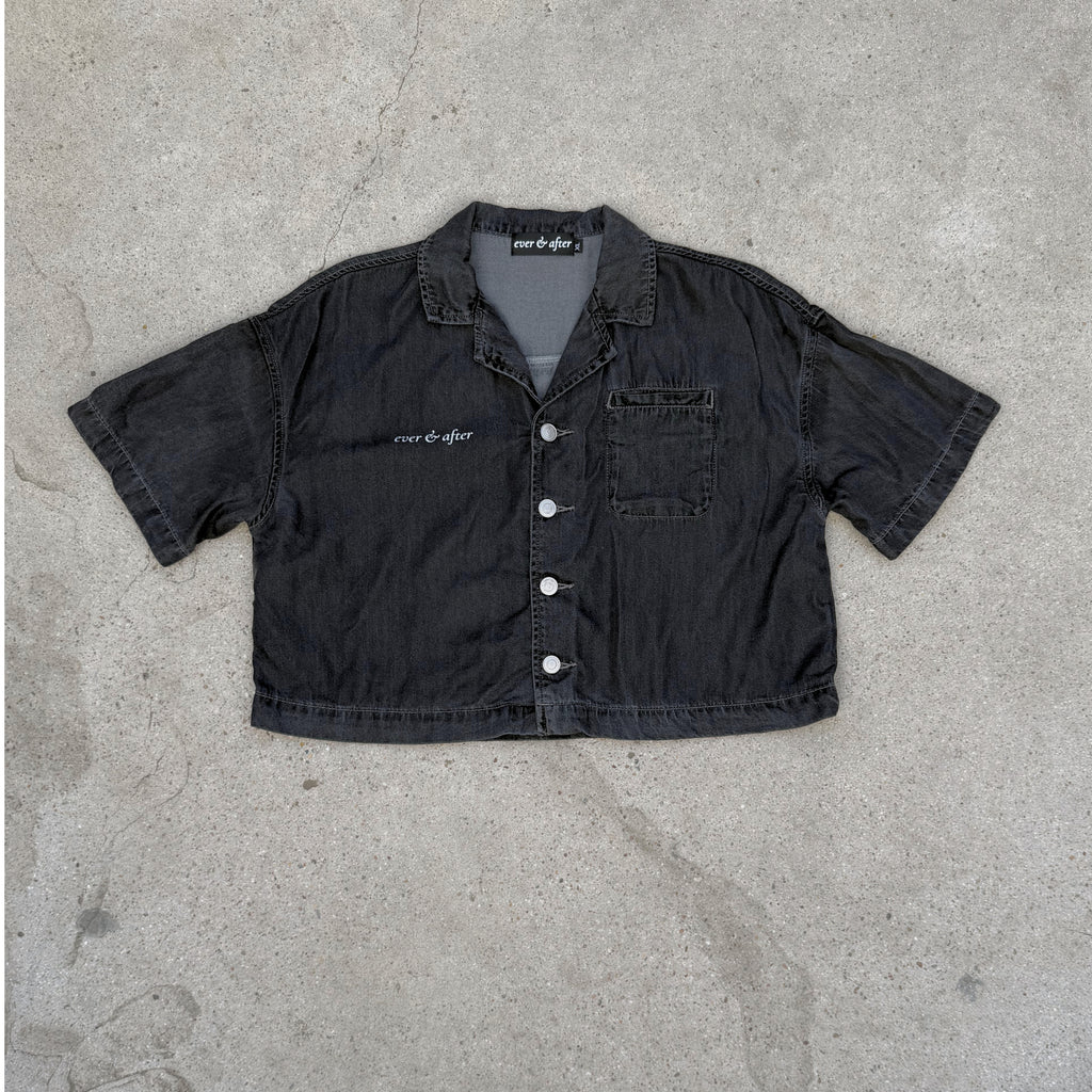 Black denim shirt with brand label on a concrete surface