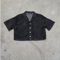 Black denim shirt with brand label on a concrete surface